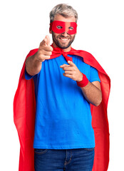 Young blond man wearing super hero custome pointing fingers to camera with happy and funny face. good energy and vibes. © Krakenimages.com