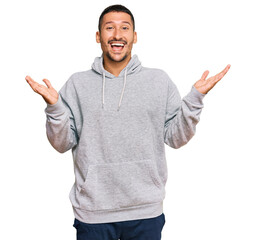 Fototapeta premium Handsome man with tattoos wearing casual sweatshirt celebrating victory with happy smile and winner expression with raised hands