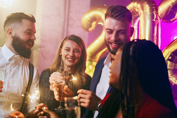 Multiracial people holding champagne glasses and sparklers in the club