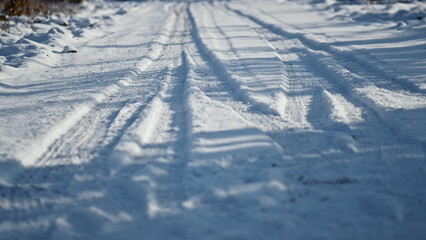 Fototapeta na wymiar Snowy road wheel marks sunny winter day close up. Snow-covered rural roadway.