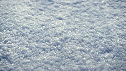 Sparkling white snow crystals covering ground wintertime close up. Snow shining.