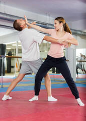 Fototapeta na wymiar European woman learning chin strike move during self-defense training.