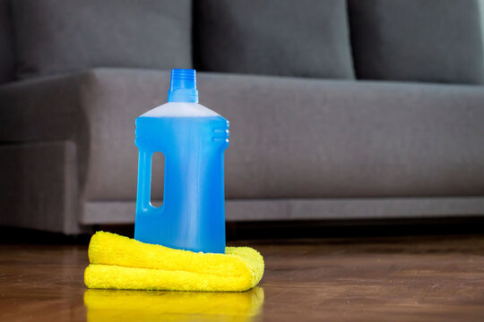 Floor cleaner in a plastic bottle and a floor cloth on the parquet floor indoors. House cleaning