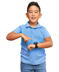 Little boy hispanic kid wearing casual clothes in hurry pointing to watch time, impatience, upset...
