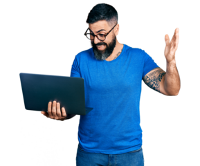 Hispanic man with beard working using computer laptop celebrating victory with happy smile and winner expression with raised hands
