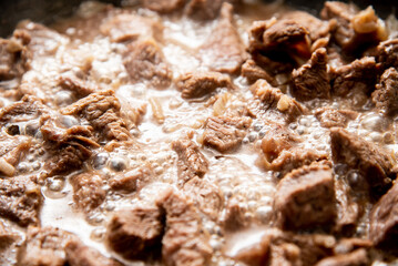 close-up beautiful large pieces of fried meat with onions in a pan