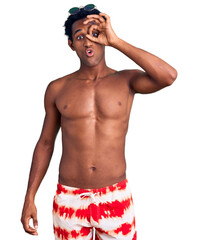 Fototapeta premium African handsome man wearing swimsuit and sunglasses doing ok gesture shocked with surprised face, eye looking through fingers. unbelieving expression.
