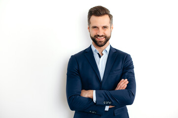 Portrait of a handsome positive caucasian successful bearded business man in a suit, seo, banker, broker, standing over isolated white background with arms crossed, looking at camera, smiling friendly - obrazy, fototapety, plakaty