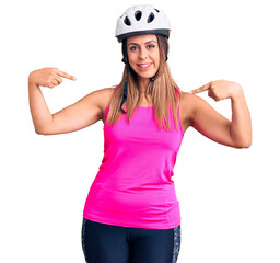 Young beautiful woman wearing bike helmet looking confident with smile on face, pointing oneself with fingers proud and happy.
