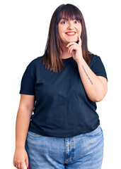 Young plus size woman wearing casual clothes looking confident at the camera with smile with crossed arms and hand raised on chin. thinking positive.