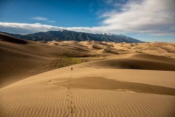 Fototapeta na wymiar Footsteps Lead To Hiker Crossing The Sand Dunes