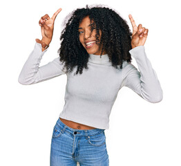Young african american girl wearing casual clothes smiling amazed and surprised and pointing up with fingers and raised arms.
