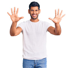 Young latin man wearing casual clothes showing and pointing up with fingers number ten while smiling confident and happy.
