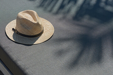 Fototapeta na wymiar Stylish straw hat on grey sunbed outdoors, space for text