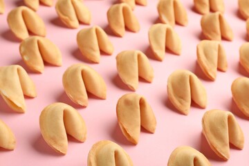 Many tasty fortune cookies with predictions on pink background