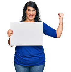 Plus size brunette woman holding blank empty banner pointing finger to one self smiling happy and proud