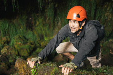 Hiker man wearing a helmet and gloves inside a cavern