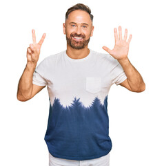 Handsome middle age man wearing casual tie dye tshirt showing and pointing up with fingers number seven while smiling confident and happy.