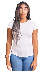 Obraz premium Young african american woman with braids wearing casual clothes making fish face with lips, crazy and comical gesture. funny expression.