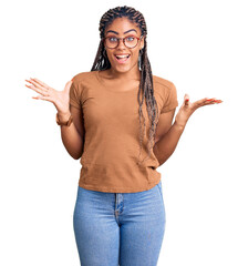 Young african american woman with braids wearing casual clothes and glasses celebrating victory...