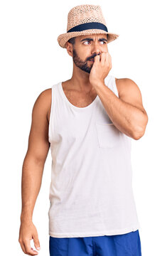 Young hispanic man wearing casual summer hat looking stressed and nervous with hands on mouth biting nails. anxiety problem.