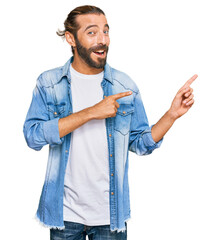 Attractive man with long hair and beard wearing casual denim jacket smiling and looking at the...