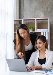 Two young Asian businessmen are excited about their success in winning online. and happy from good news e-mails in notebooks Inspired by great deals or new opportunities.