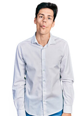 Young hispanic business man wearing business clothes making fish face with lips, crazy and comical gesture. funny expression.