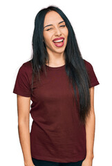 Young hispanic girl wearing casual t shirt winking looking at the camera with sexy expression, cheerful and happy face.