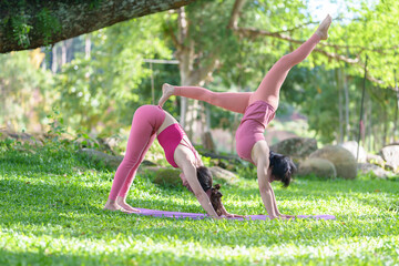 Fototapeta premium Female yoga trainer helps female, group training participant, do right perform correctly pose, class in park by experienced young woman instructor wellness concept., peace relaxation, woman happiness