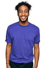 Young african american man with beard wearing casual purple t shirt with a happy and cool smile on...