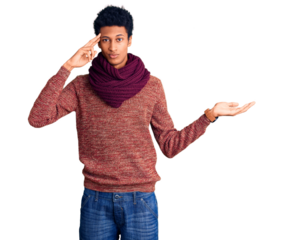 Young african american man wearing casual winter sweater and scarf confused and annoyed with open palm showing copy space and pointing finger to forehead. think about it.