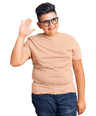 Little boy kid wearing casual clothes and glasses waiving saying hello happy and smiling, friendly welcome gesture © Krakenimages.com