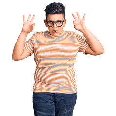 Little boy kid wearing casual clothes and glasses looking surprised and shocked doing ok approval symbol with fingers. crazy expression