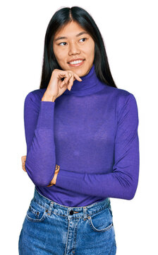 Beautiful young asian woman wearing casual clothes looking confident at the camera smiling with crossed arms and hand raised on chin. thinking positive.