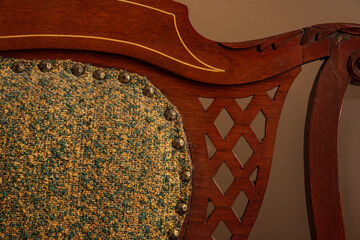 Antique chair closeup with intricate woodwork and green upholstery  