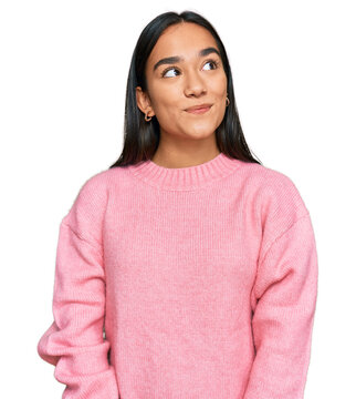 Young asian woman wearing casual winter sweater smiling looking to the side and staring away thinking.