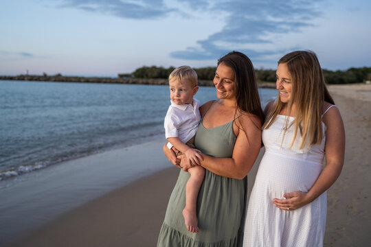 Lesbian family walking on the beach smiling