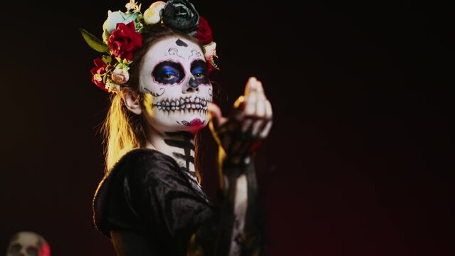 Flirty goddess of dead calling and luring victims, looking like la cavalera catrina with skull black and white make up. Holy santa muerte costume on mexican holiday horror celebration. Handheld shot.