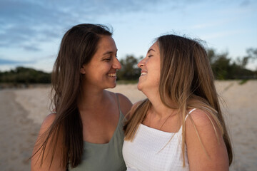 lesbian couple smiling at each other on the beach