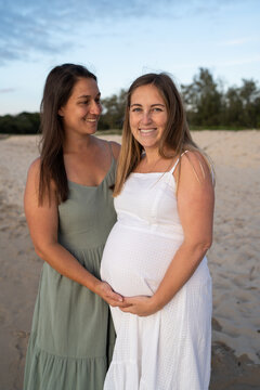 lesbian couple pregnant smiling at the beach