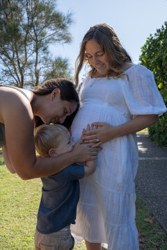 lesbian family touching pregnant mother belly