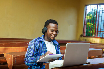 Attractive young black African male student using laptop for e-learning