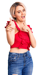 Young beautiful blonde woman wearing casual clothes pointing fingers to camera with happy and funny face. good energy and vibes.