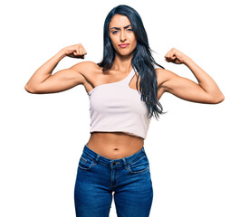 Beautiful hispanic woman wearing casual clothes showing arms muscles smiling proud. fitness concept.