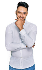 Young arab man wearing casual clothes looking confident at the camera smiling with crossed arms and hand raised on chin. thinking positive.