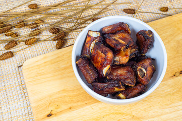Top view of grilled pork ribs in a bowl on a wooden board, Obesity causes, Cancer causes, Unhealthy food.