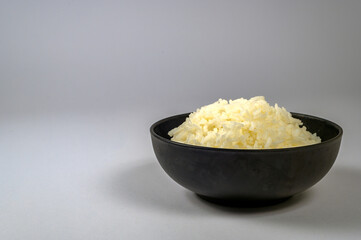Rice in a black bowl on a white background.