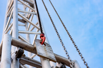 Close-up of a hook with a metal chain on a metal frame of stage lighting in a city square