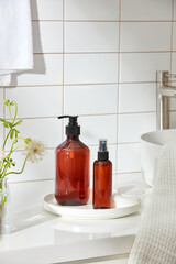 Bottles of body care on the white tray next to the sink. flowers, cotton towel on the table inside the bathroom background
